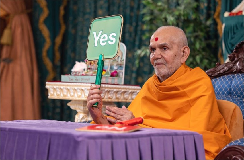 Mahant Swami Maharaj taking part in an assembly, holding up an answer card