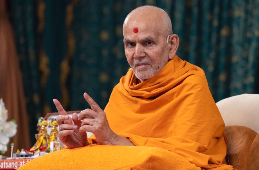 Mahant Swami Maharaj seated beside the murtis during an assembly